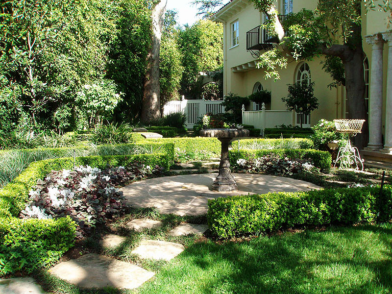 Formal garden with fountain, boxwood borders, and flagstone paths