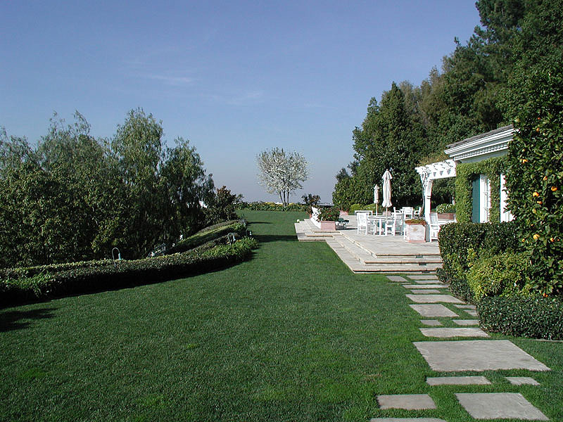 Stone pathway across manicured lawn to dining pergola